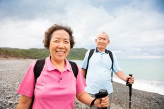 Senior couple of Asian descent hiking by ocean